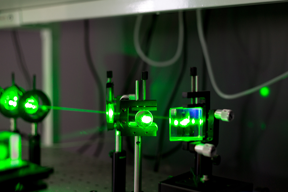 A green laser shines through several pieces of glass